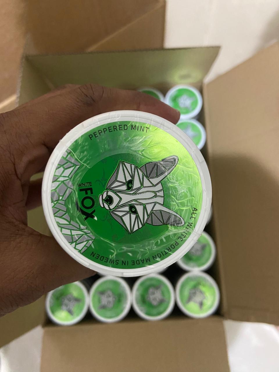 Green container with a fox design held by a hand, with more containers in the background