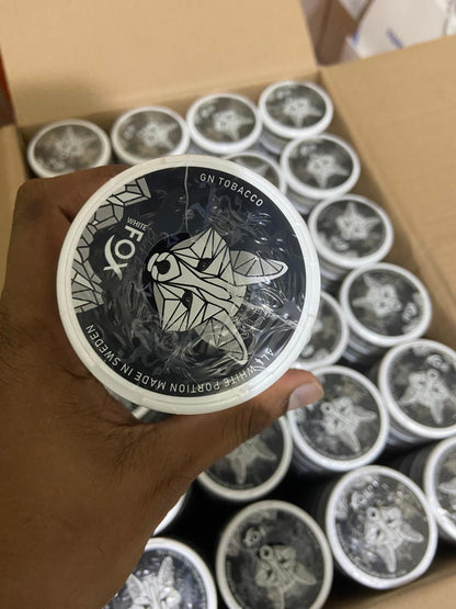 Hand holding a container of GN Tobacco with a box of similar containers in the background