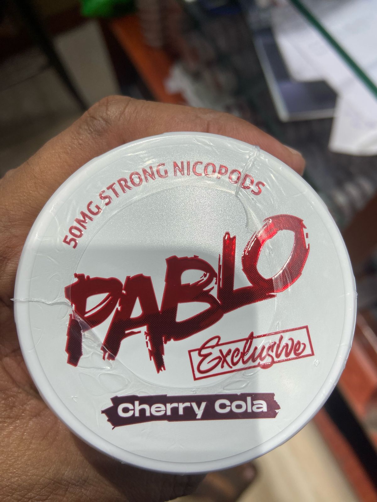Pablo Nicotine Pouches Cherry Cola flavor 50mg Strong Nicopods Container held by a hand